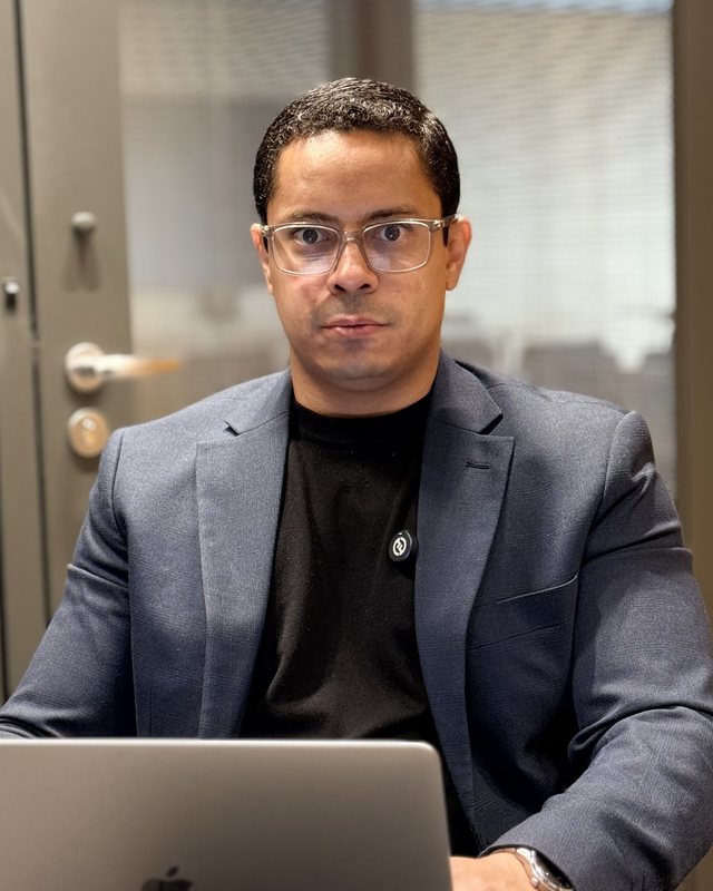 Hugo Rodrigues, de blazer, trabalhando no notebook